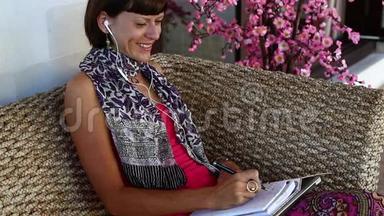 有笔记本电脑的女人在别墅外面的教练的笔记本上做笔记。 巴厘岛。